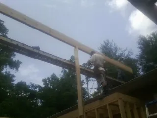 Carpenter setting a ridge beam over a new addition frame — Ice Dam Removal by Roofing Brothers in Ray