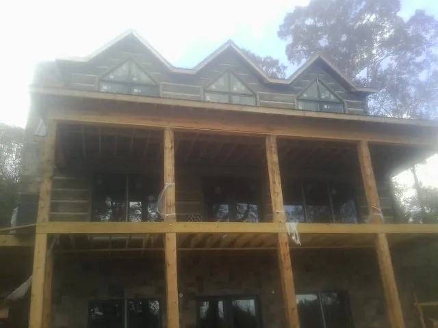 Dormers and porch framing on a large log home under construction — Roof Coating work by our crew in Ray