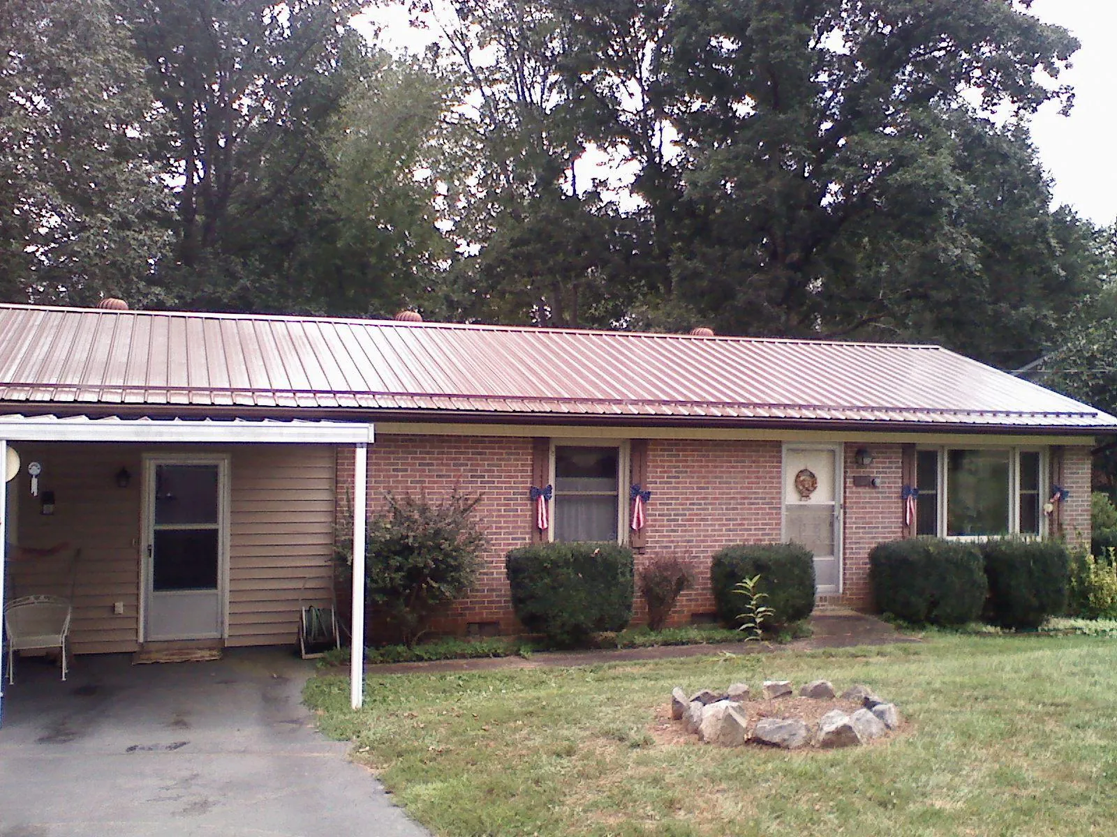 Bronze metal roof and carport on a brick ranch home — Roof Repair work by our crew in Ray